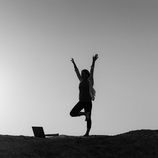 Silhouette of a person in a yoga warrior pose at sunrise.